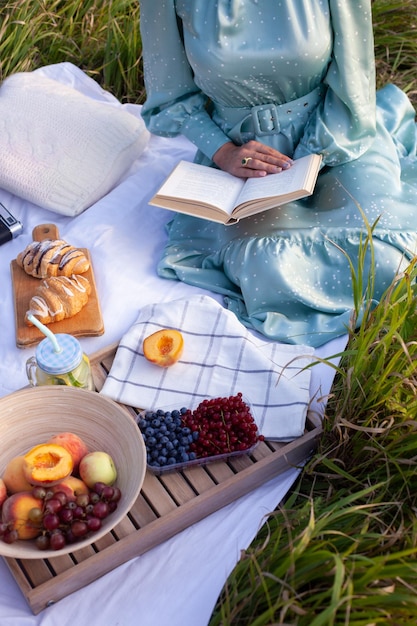 Una mujer vestida de azul se sienta en un picnic en un parque con vista panorámica