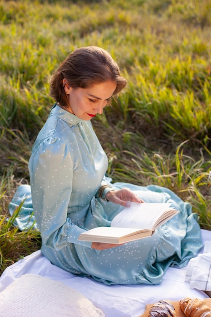 Una mujer vestida de azul se sienta en un picnic en un parque con vista panorámica