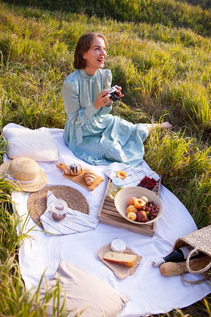 Una mujer vestida de azul se sienta en un picnic en un parque con vista panorámica