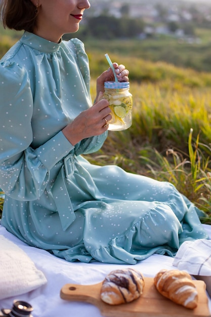 Una mujer vestida de azul se sienta en un picnic en un parque con vista panorámica