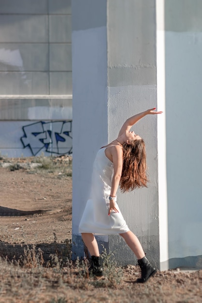 Mujer vestida de blanco y con el pelo largo posando bajo el puente contra el fondo de hormigón