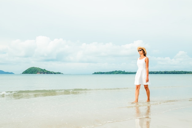 Mujer vestida de blanco en una playa tropical