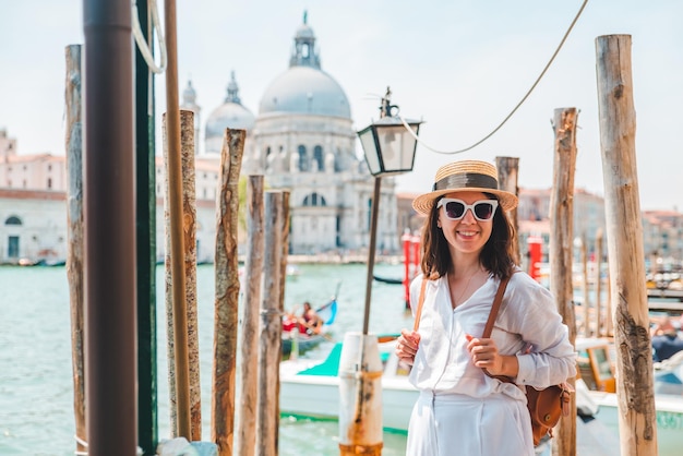 Mujer vestida de blanco con sombrero de paja en el muelle basílica santa maria della salute en el fondo