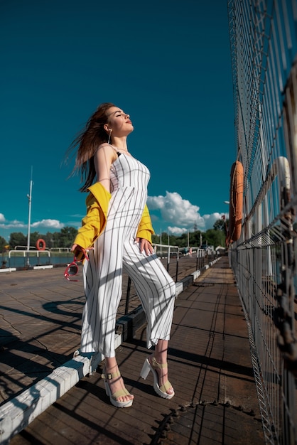 Una mujer vestida con una blusa amarilla y gafas disfrutando del agradable clima soleado mientras camina