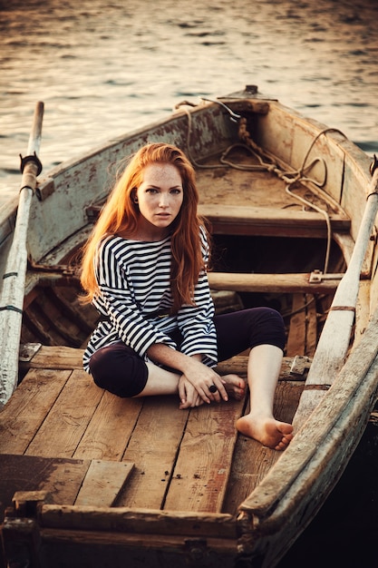 mujer vestida con una camisa de rayas marinas se sienta en un bote