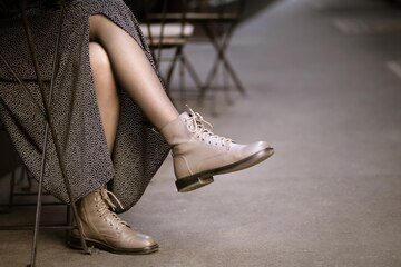 Mujer con elegante y botas sentada en un café de calle | Foto Premium