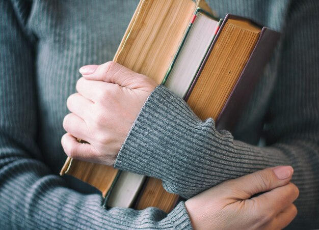 La mujer vestida de gris tiene libros antiguos en la mano