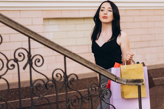 Foto mujer vestida de moda con bolsas de compras de color en las escaleras, concepto de compras