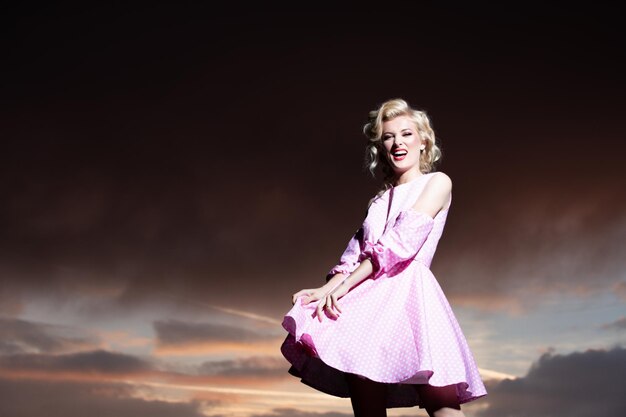 Mujer vestida de monroe en un cielo dramático. Mujer atractiva en traje de moda afuera. Foto de moda al aire libre de una joven hermosa dama disfrutando de la primavera.