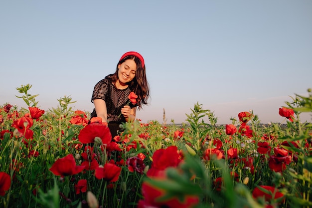 Mujer vestida de negro al atardecer en el campo de flores de amapola