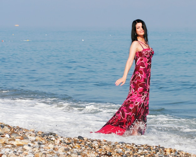 Mujer vestida de rosa en la playa del mar