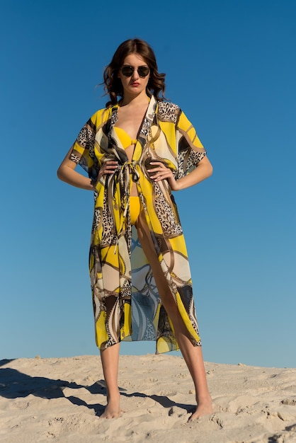 Una mujer con un vestido amarillo se para en el desierto.