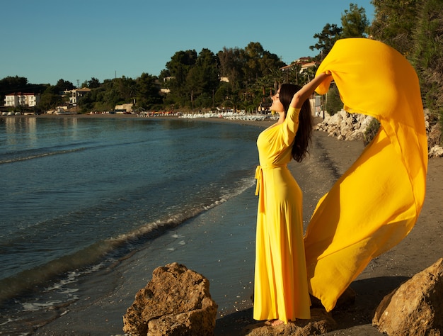 Mujer con vestido amarillo en una playa.