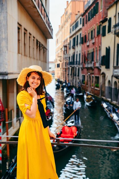 Mujer en vestido amarillo en el puente con vista al canal de venecia