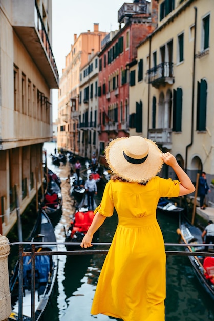 Mujer en vestido amarillo en el puente con vista al canal de venecia