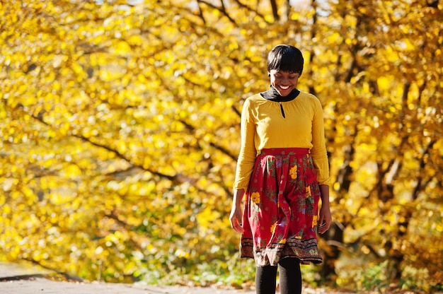 Mujer en vestido amarillo y rojo en el parque otoño otoño dorado