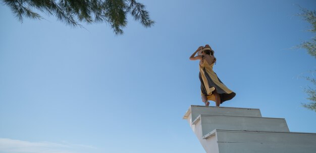 Mujer en vestido amarillo subiendo por la escalera al atardecer.