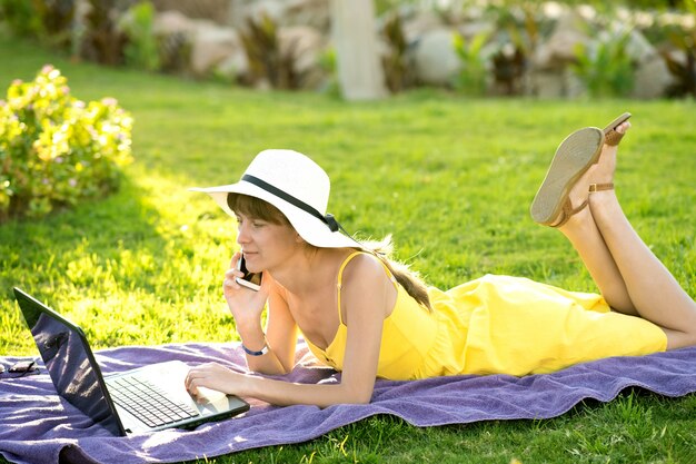 Mujer en vestido amarillo de verano con un portátil