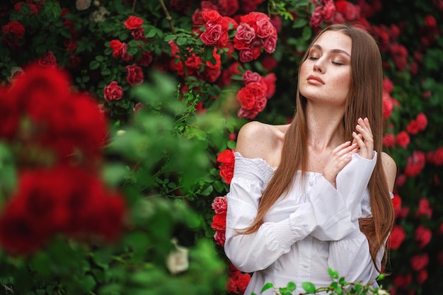 mujer en un vestido en arbusto de rosas