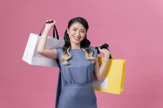 Mujer con vestido azul en el fondo feliz disfrutando de las compras con bolsas de colores