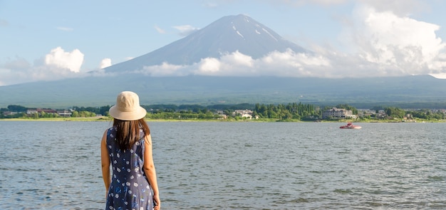 mujer en vestido azul con sombrero viendo la montaña Fuji en verano