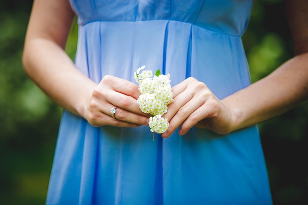 Una mujer con un vestido azul sostiene un ramo de flores.