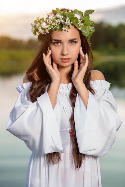 Mujer con vestido blanco en el agua. Arte Mujer con corona en la cabeza en el río. Corona en la cabeza, tradiciones eslavas y paganismo.