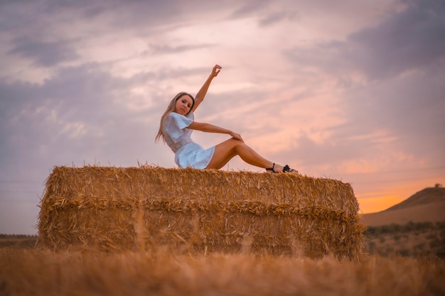 Mujer con un vestido blanco en un campo de paja seca