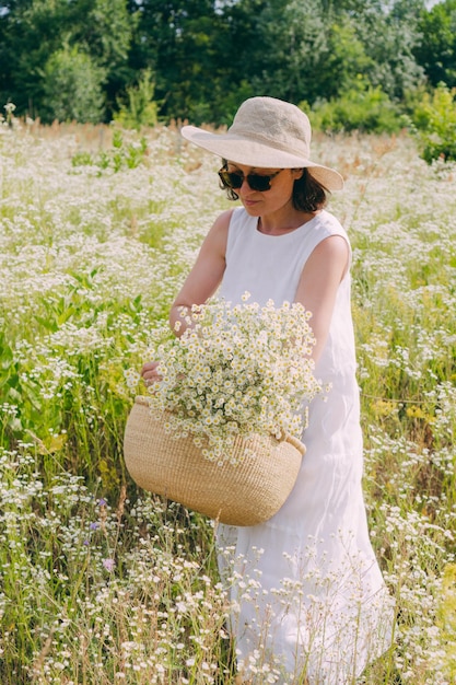 Mujer con un vestido blanco cerca de un campo de flores con ramo de margaritas Retrato de una mujer de 48 años