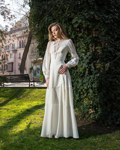 Una mujer con un vestido blanco se encuentra en un parque.