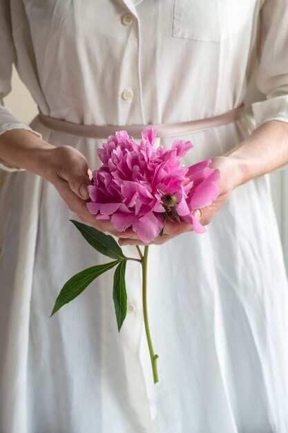 Mujer en vestido blanco con flor de peonía pion rosa