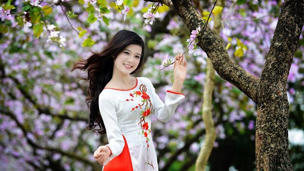 una mujer en un vestido blanco con una flor roja en el frente