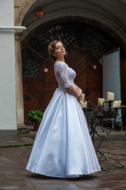 Una mujer con un vestido blanco se para frente a una puerta.