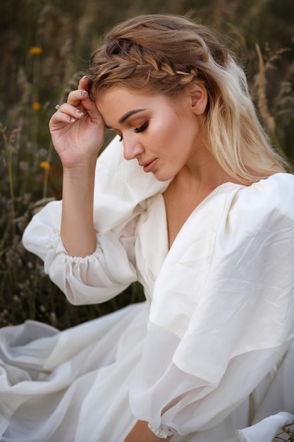 Mujer con un vestido blanco en la hierba al atardecer