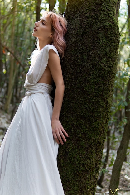 Una mujer con un vestido blanco en medio del bosque.