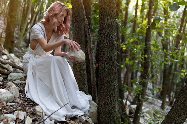 Una mujer con un vestido blanco en medio del bosque.