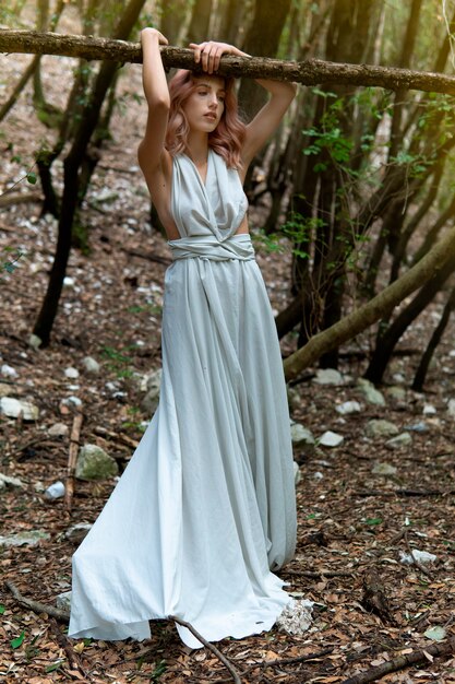 Una mujer con un vestido blanco en medio del bosque.