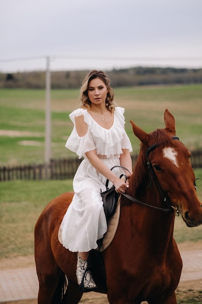 Una mujer con un vestido blanco montando a caballo en un campo