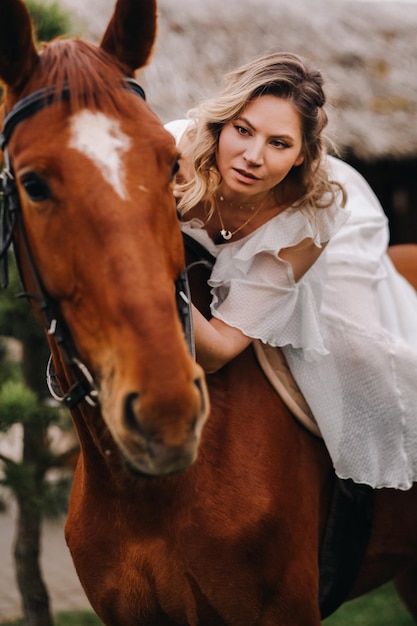 Una mujer con un vestido blanco montando un caballo cerca de una granja