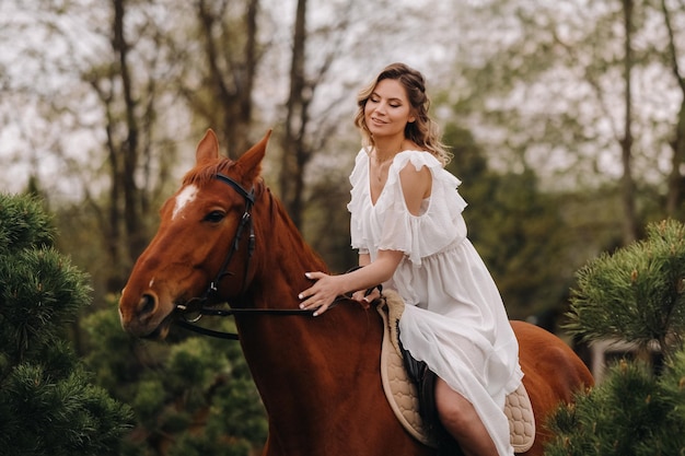 Una mujer con un vestido blanco montando un caballo cerca de una granja