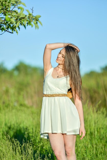 una mujer con un vestido blanco de pie bajo un árbol