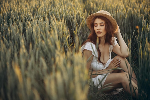 Mujer con vestido blanco sentada en el campo verde