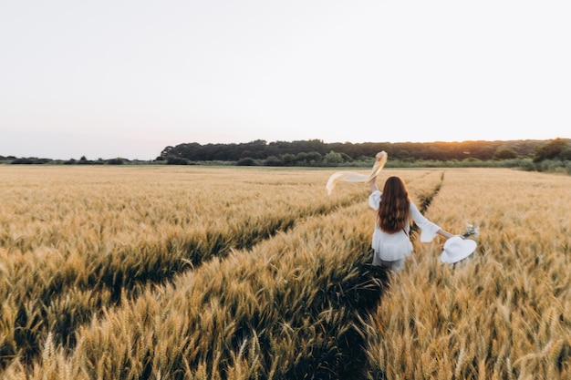 mujer con vestido blanco y sombrero blanco en un campo de trigo