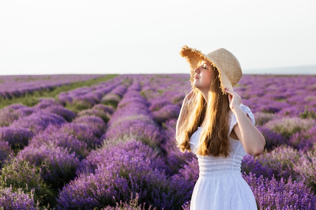 Mujer con vestido blanco y sombrero de paja en campo de lavanda