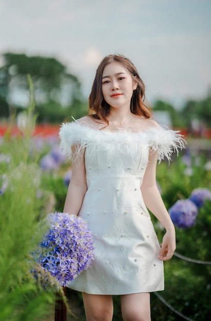 Una mujer con un vestido blanco sostiene un ramo de flores.