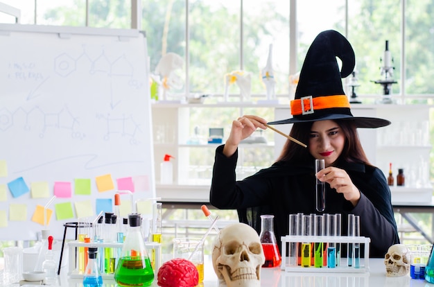 Mujer con vestido de bruja y probeta en laboratorio