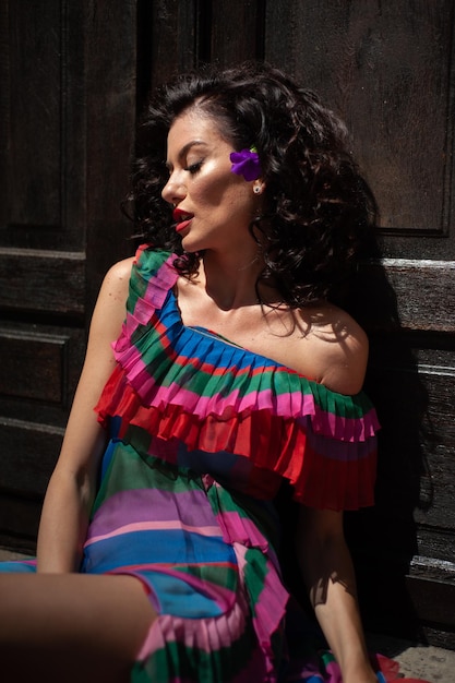 Una mujer con un vestido colorido y una flor en el pelo.