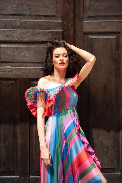 Foto una mujer con un vestido colorido se para frente a una puerta.