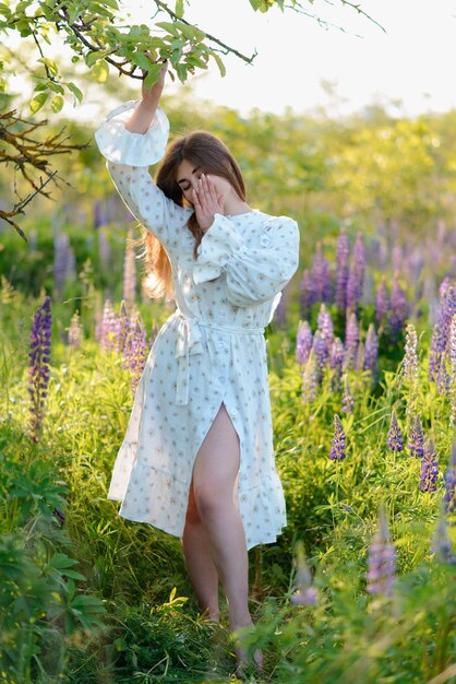 Una mujer con un vestido elegante posando en un campo de lupinos