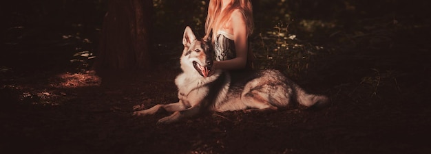 La mujer con un vestido está sentada con un perro.